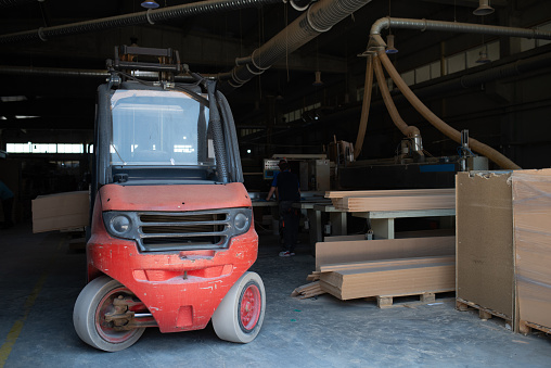 A forklift efficiently transports wooden products into a woodworking facility, where they are destined for the production of high-quality doors, showcasing the seamless integration of logistics and machinery in the woodworking industry