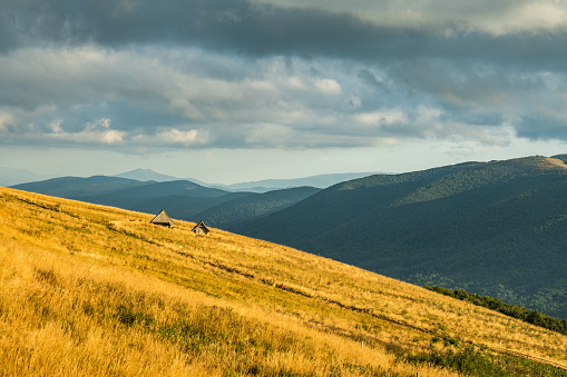 Beautiful scenery of grass fields covering a side of a hill or a mountain with mountain range in the distance