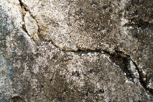 A weathered and cracked concrete wall, showcasing the passage of time and the impact of the elements on its surface