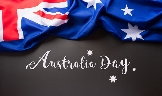 Happy Australia day concept. Australian flag and the text against dark background. 26 January.