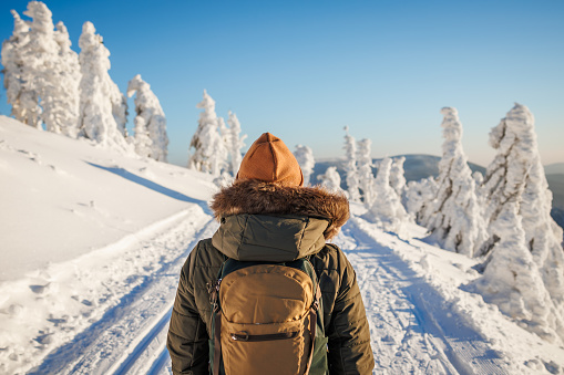 Woman with backpack hiking in winter mountains. Hiker walk in snow in nature