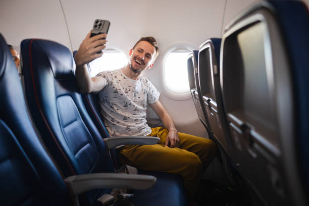 istock Young man taking selfies in an airplane while flying for vacation 1835006838