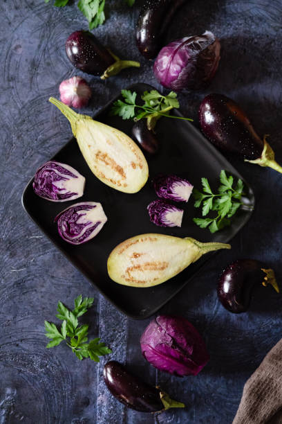 istock Assortment raw organic of purple vegetables mini eggplants, spring onion, beetroot, radicchio salad, plums, kohlrabi, flower salt over dark metal background. Top view with space. Food frame 1835017795