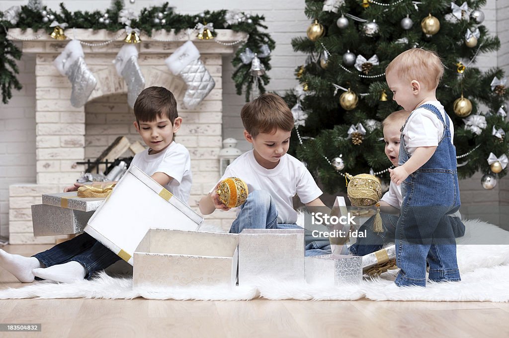 Children under the Christmas tree with gifts and toys Children make out gifts at Christmas tree Decoration Stock Photo