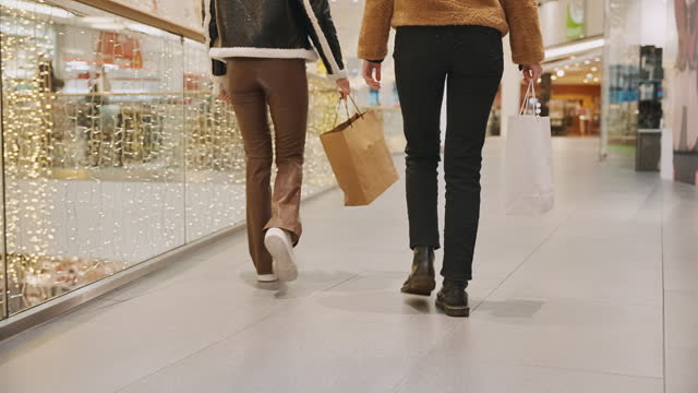 SLO MO Low Section of Female Friends Holding Shopping Bags While Walking in Shopping Mall During Christmas