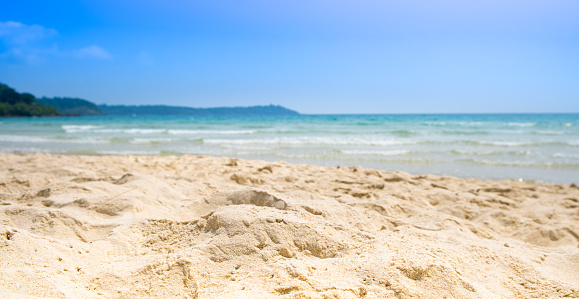 Beach sand background for summer vacation concept. Beach nature and summer seawater with sunlight light sandy beach Sparkling sea water contrast with the blue sky