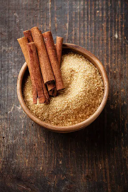 Cinnamon sticks and cane sugar on wooden background