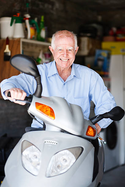istock Smiling old man sits astride his motor scooter 183505846