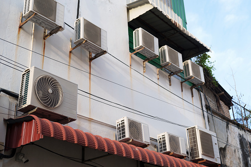 Air conditioners of various sizes are mounted on a bracket attached to the building wall