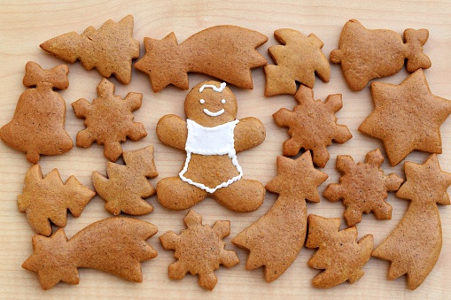 Smiling gingerbread man surrounded by undecorated gingerbreads. Homemade Christmas baking