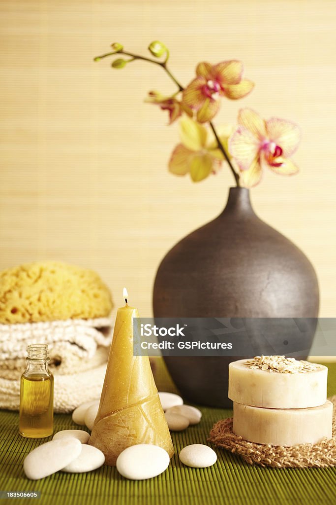 Spa still life of orchid flower and candel in bathroom "Spa still life of orchid flower in bathroom with stack of towels, candle, essential oil, oatmeal soap, bath sponge, and white pebbles" Alternative Medicine Stock Photo