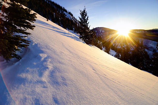 Scenic Winter Mountain Sunset.  View of setting sun with warm late afternoon light.  Cool lens flare effect from using wide angle lens.  Captured as a 14-bit Raw file. Edited in ProPhoto RGB color space.