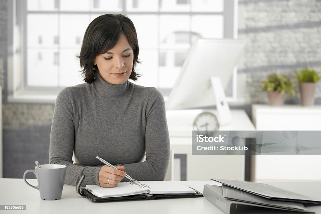 Joven mujer escribiendo en organizador personal en su hogar - Foto de stock de 20 a 29 años libre de derechos