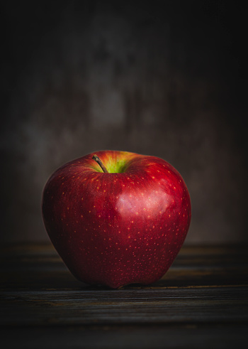 close-up of red apple, organic, on natural wood table with dark background, copy space