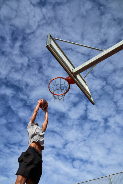 istock Man athlete jumping while dunking basketball against sky 1835070892