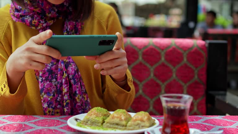 Young Woman Taking A Picture Of A Plate Of Baklava With Pistachios In Istanbul