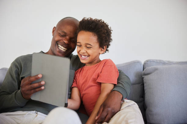 istock Dad and his son laughing at a video on a tablet at home 1835080179