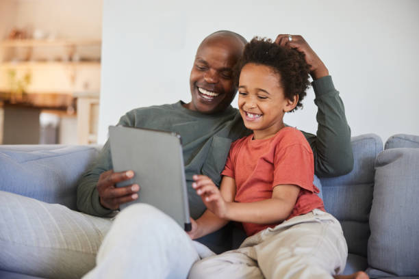 istock Laughing dad and his son watching at a video on a tablet at home 1835081240