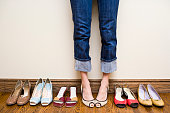Woman stands wearing heels with her collection of Shoes
