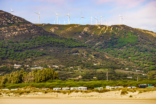 Coastal landscape. Many caravan vehicles camping on sea coast. Wind turbines oh hill. Mediterranean region of Costa del Sol, Spain.