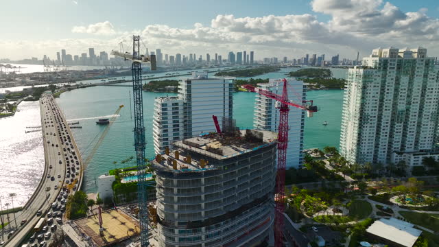 New construction site of developing residence in American urban area. Industrial tower lifting cranes in Miami, Florida. Concept of housing growth in the USA