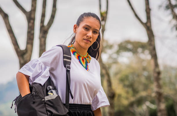 istock woman with hair up while outdoors looking for an object in her backpack 1835129205