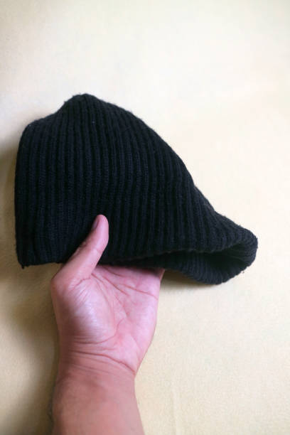 istock A hand holding a Black beanie, made from knitted fabric. on a white or cream background 1835129369
