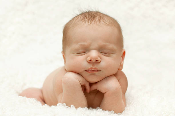 Sleeping newborn posed with head on hands stock photo