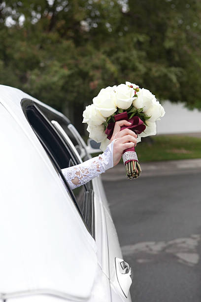 Bride holding her flower bouquet through a window in a limo.