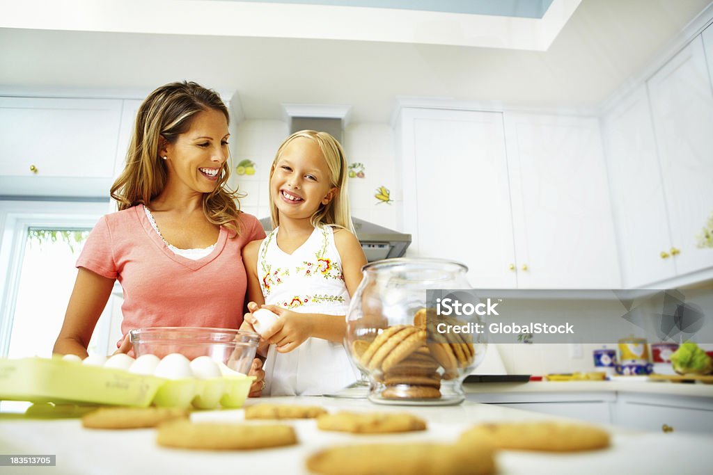 Mãe e filha com cookies em pé na cozinha - Foto de stock de Brilhante - Luminosidade royalty-free