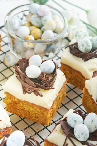istock Easter carrot cake bars decorated with chocolate nest and chocolate candy eggs blossoming cherry or apple flowers on rustic light wooden backgrounds. Easter holiday meal. Traditional Easter food. 1835148033