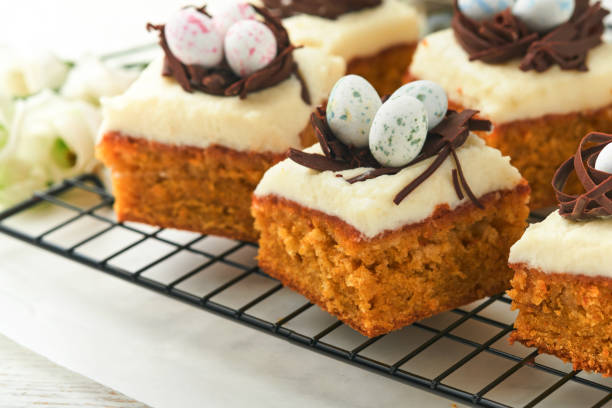 istock Easter carrot cake bars decorated with chocolate nest and chocolate candy eggs blossoming cherry or apple flowers on rustic light wooden backgrounds. Easter holiday meal. Traditional Easter food. 1835148613