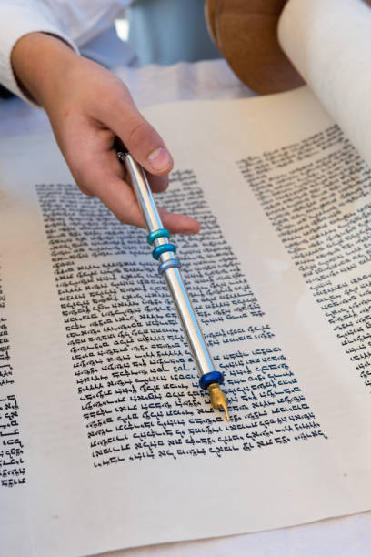 Reading from a Torah scroll using a pointer or yad A boy reading from the Torah during his bar mitzvah celebration in Israel, holds a silver yad, a pointer used to guide the reader through the ancient Hebrew text. bar mitzvah stock pictures, royalty-free photos & images