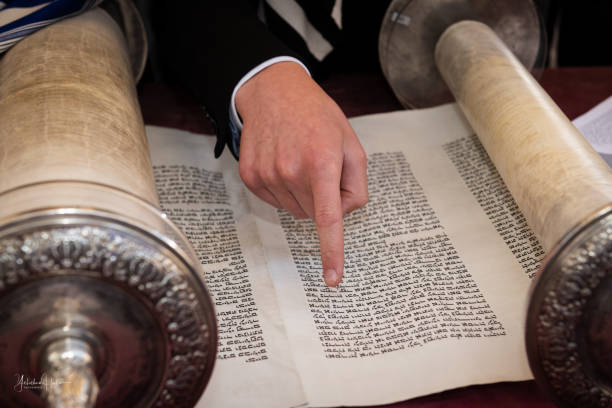 istock A man reading from a Torah scroll uses his finger as a guide through the Hebrew text. 1835150221