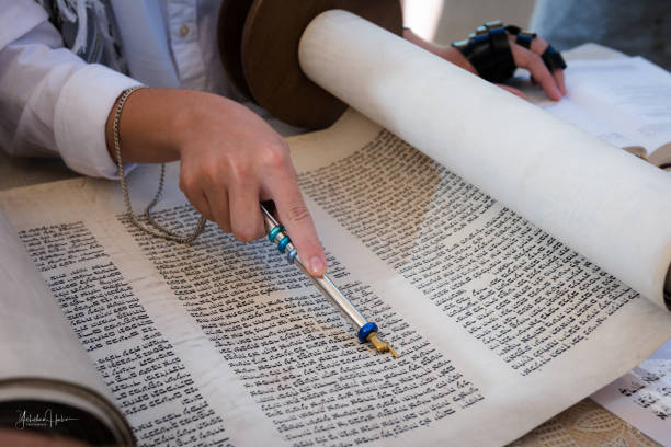 Reading from a Torah scroll using a pointer or yad A man reading from the Torah uses a pointer or yad to guide him through the Hebrew text. legs against the wall stock pictures, royalty-free photos & images