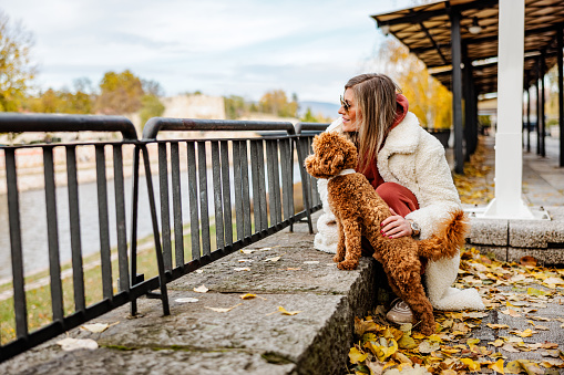 Woman with dog enjoys autumn by the river in the city