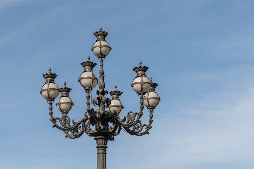 Metal old-fashioned lamppost against blue sky
