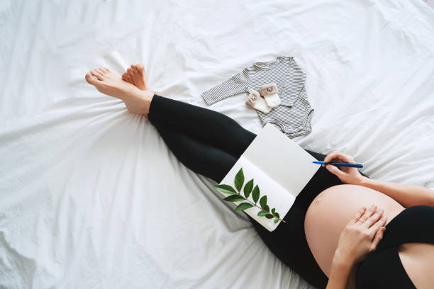 istock Pregnant woman with beautiful belly makes notes or check list in paper diary. 1835183471