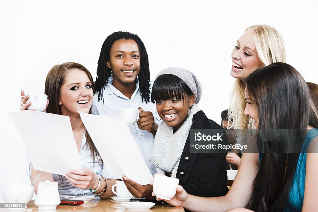 Group of young people delighted by documents, perhaps exam results "This group of young people in a coffee shop are delighted by some documents they are holding, possibly exam results, but certainly good news." 20-29 Years Stock Photo