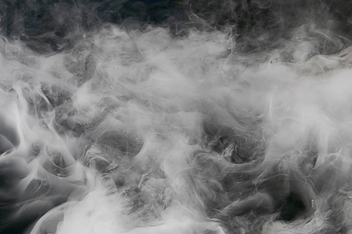 Blurred white water vapor on black background. Abstract isolated water vapor with copy space. Flow of smoke steam on black background.