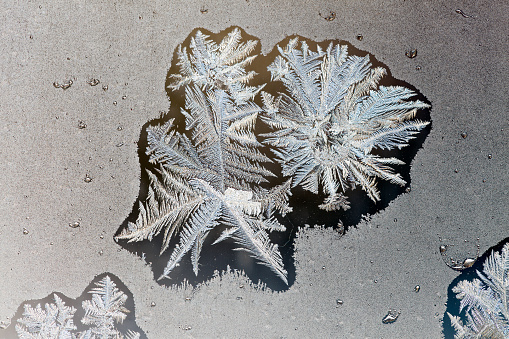 White, grey, blue ice crystals on a window pane.