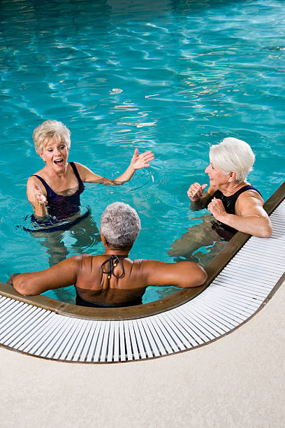 multiraciale femme senior détente dans la piscine - sc0450 photos et images de collection