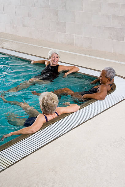 multiraciale femme senior détente dans la piscine - sc0450 photos et images de collection