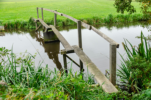Oudewater, The Netherlands, October 8, 2023: narrow wooden pedestrian bridge across a ditch as part of a hiking trail