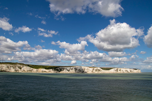 Landscape view of white cliffs of Dover from the sea,with a beautiful cloudy sky and sun