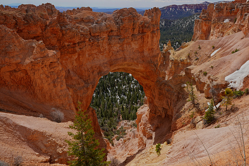 People trekking the Navajo loop trail in Bryce Canyon National Park at sunrise with some clouds and fog. Utah, USA