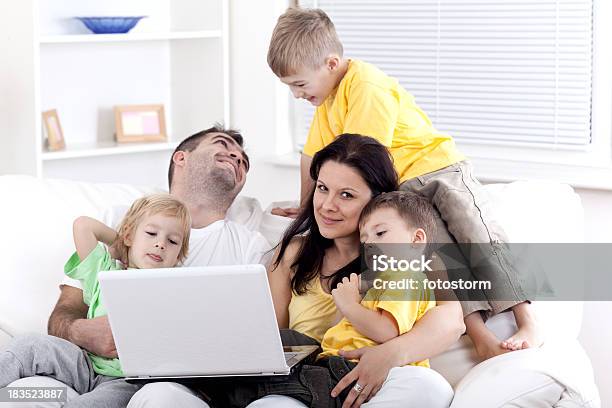 Familia Feliz Sentado En Un Sofá En La Sala De Estar Con Capacidad Para Una Computadora Portátil Foto de stock y más banco de imágenes de 30-39 años