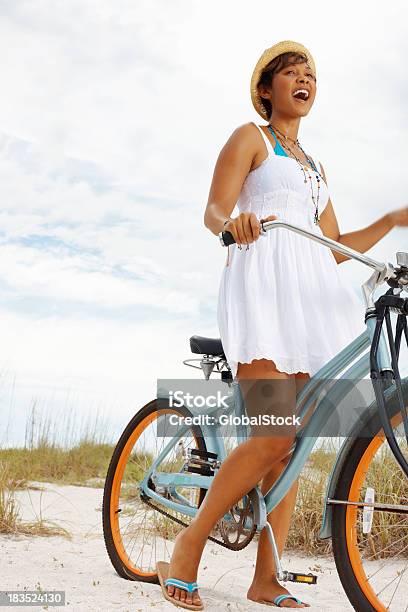 Photo libre de droit de Vélo Équitation Jeune Femme Sur La Plage Avec Ciel Nuageux banque d'images et plus d'images libres de droit de Activité de loisirs