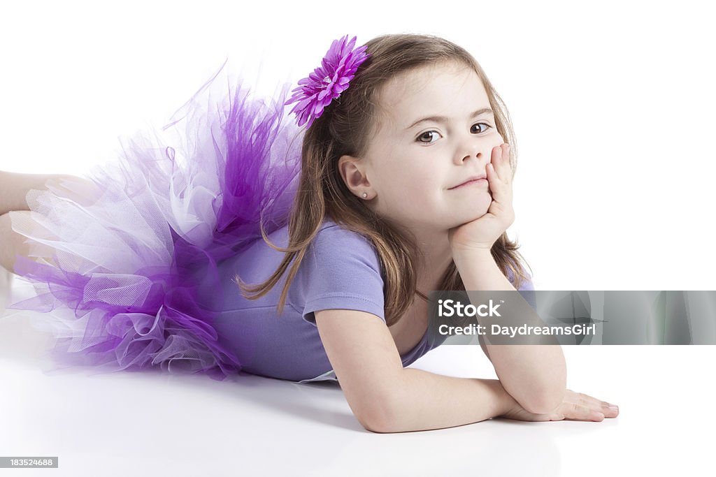 Cute Little Girl Lying on White Background Wearing Tutu Cute little girl lying on white floor. Wearing purple leotard and tutu. 4-5 Years Stock Photo