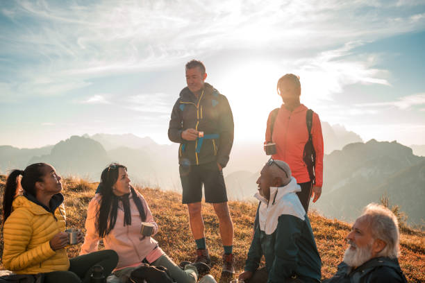 Mature hiking couple use mobile phone in mountain meadow at sunrise, springtime, Crowsnest Pass, Alberta
